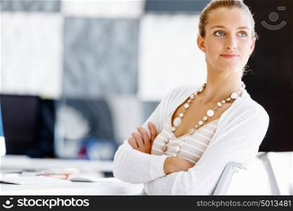 Attractive office worker sitting at desk. Attractive woman sitting at desk in office arms crossed
