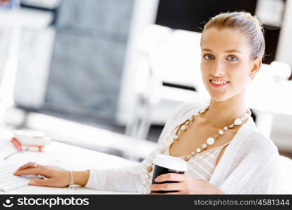 Attractive office worker sitting at desk. Attractive woman sitting at desk in office with coffee