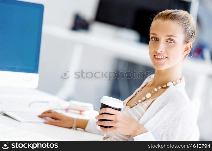 Attractive office worker sitting at desk. Attractive woman sitting at desk in office with coffee