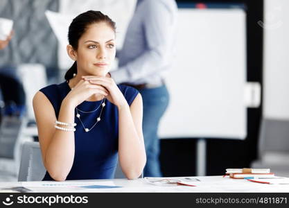 Attractive office worker sitting at desk. Attractive woman sitting at desk in office with coffee