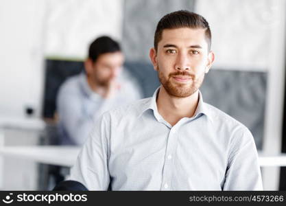 Attractive office worker sitting at desk. Young businessman sitting at desk in office