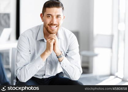 Attractive office worker sitting at desk. Young businessman sitting at desk in office