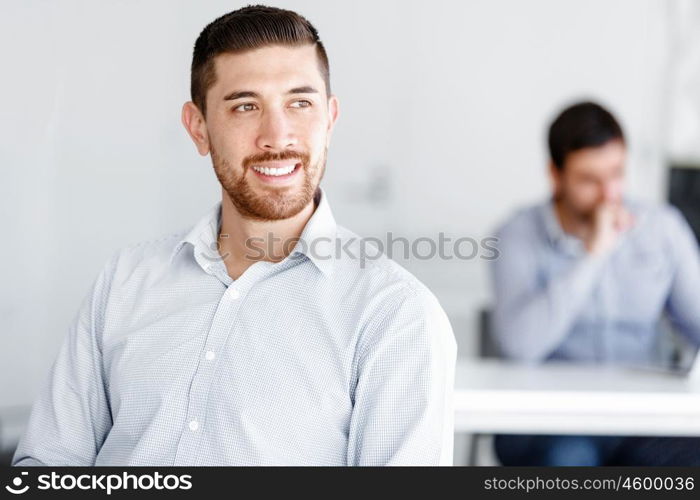 Attractive office worker sitting at desk. Young businessman sitting at desk in office