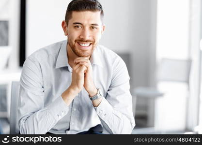 Attractive office worker sitting at desk. Young businessman sitting at desk in office