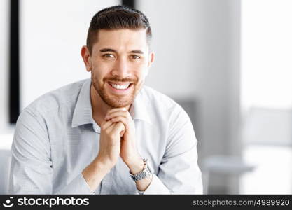 Attractive office worker sitting at desk. Young businessman sitting at desk in office