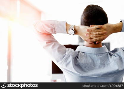 Attractive office worker sitting at desk. Young businessman sitting at desk in office