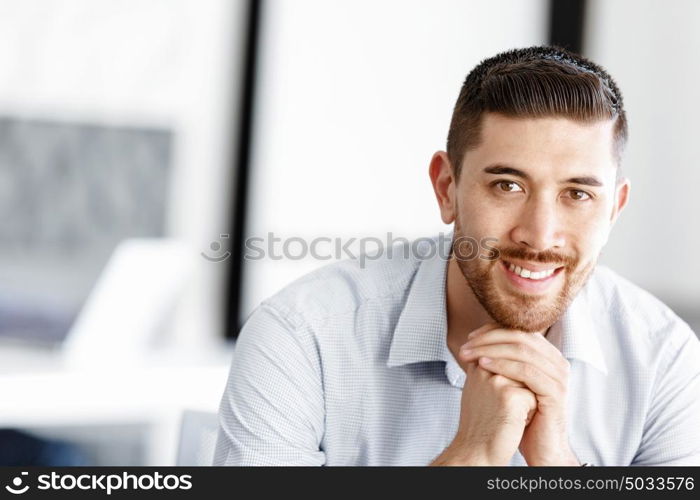 Attractive office worker sitting at desk. Young businessman sitting at desk in office