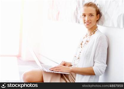 Attractive office worker sitting on floor. Attractive woman sitting on floor in office with notepad