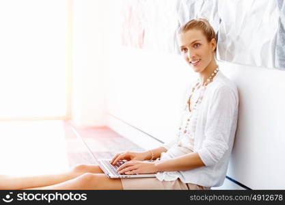 Attractive office worker sitting on floor. Attractive woman sitting on floor in office with notepad