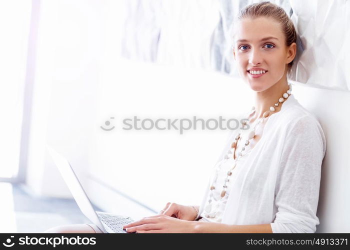 Attractive office worker sitting on floor. Attractive woman sitting on floor in office with notepad