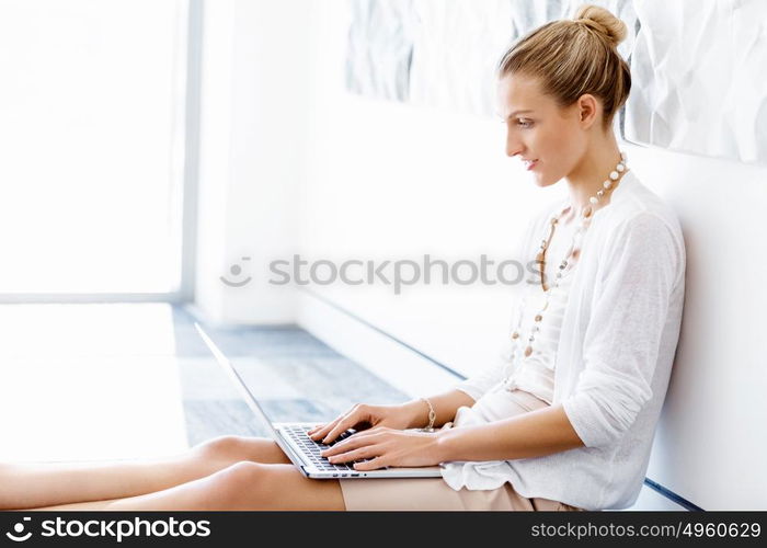 Attractive office worker sitting on floor. Attractive woman sitting on floor in office with notepad