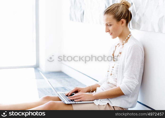 Attractive office worker sitting on floor. Attractive woman sitting on floor in office with notepad