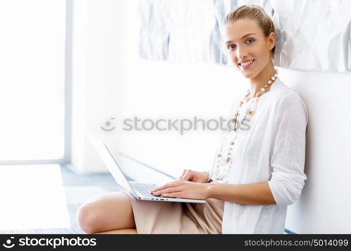 Attractive office worker sitting on floor. Attractive woman sitting on floor in office with notepad