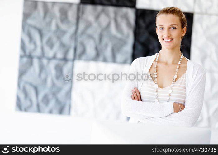 Attractive office worker standing next to window. Attractive woman sitting in office standing next to window