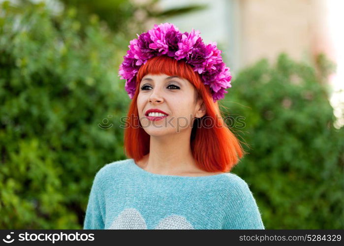 Attractive red haired girl with wreath of flowers in a park