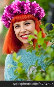 Attractive red haired girl with wreath of flowers in a park