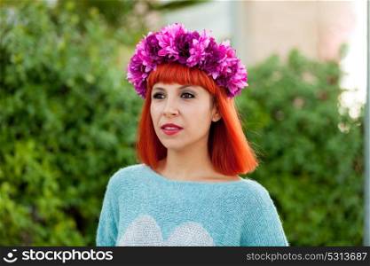 Attractive red haired girl with wreath of flowers in a park