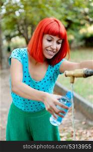 Attractive redhead girl filling a bottle of water in a fountain