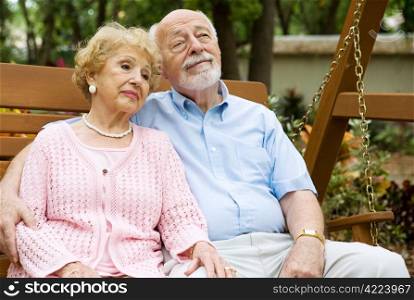 Attractive senior couple relaxing together on a swing in the park.