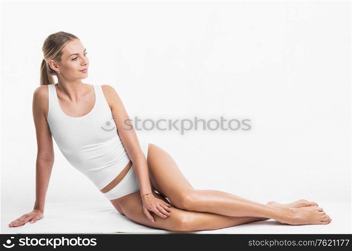 Attractive sensitive slim woman sitting in white cotton lingerie underwear isolated on white background. Woman sitting in white underwear