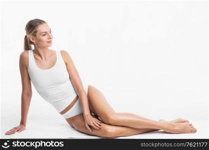 Attractive sensitive slim woman sitting in white cotton lingerie underwear isolated on white background. Woman sitting in white underwear