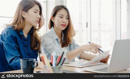 Attractive smart creative Asian business women in smart casual wear working on laptop while sitting on desk in office. Women work at office concept.