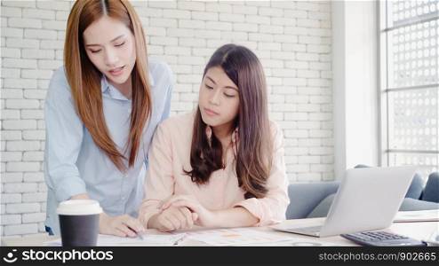 Attractive smart creative Asian business women in smart casual wear working on laptop while sitting on desk on office desk. Lifestyle women work at office concept.