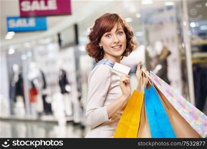 Attractive smiling curly woman on shopping with a credit card