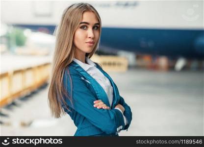 Attractive stewardess in uniform poses against airport building. Air hostess in suit near terminal. Flight attendant occupation. Stewardess in uniform against airport building