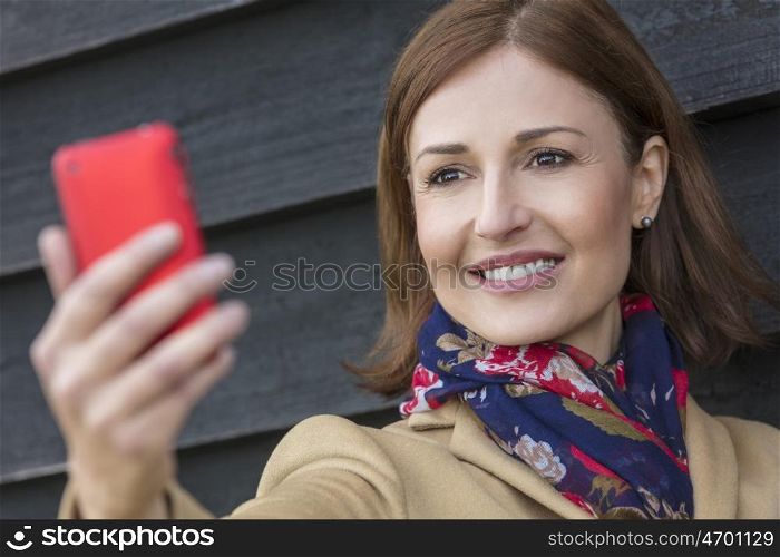 Attractive, successful and happy middle aged woman female taking selfie photograph on mobile cell phone