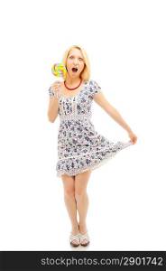 Attractive surprised blonde with lollipop holding her dress, looking like a littile girl