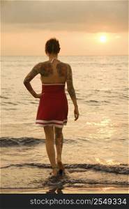 Attractive tattooed Caucasian woman on beach at sunset in Maui, Hawaii, USA.