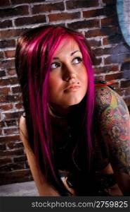 Attractive tattooed girl studio portrait, brick wall at background