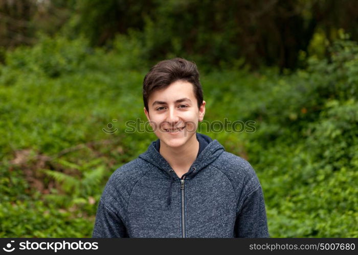 Attractive teenager guy in a park with green plants of background