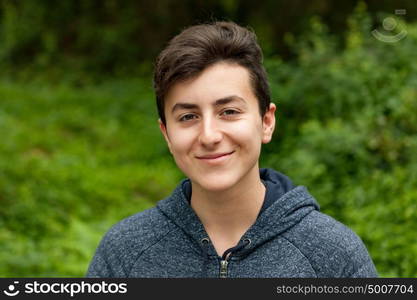 Attractive teenager guy in a park with green plants of background