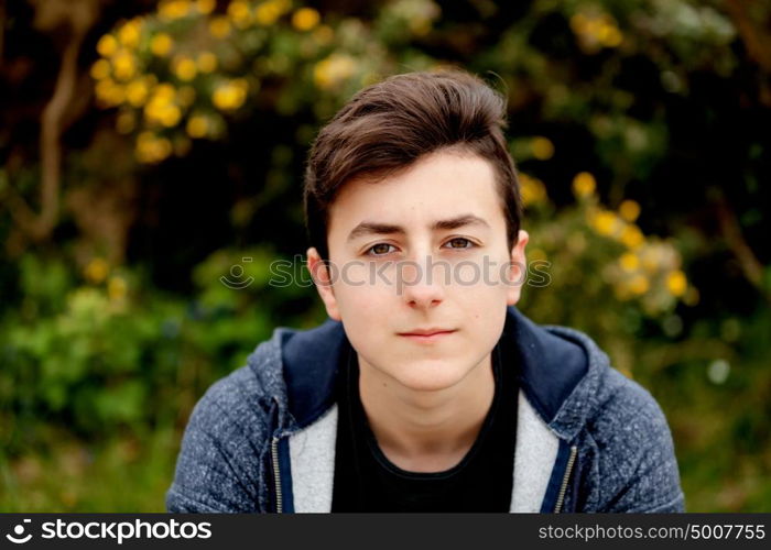 Attractive teenager guy in a park with green plants of background