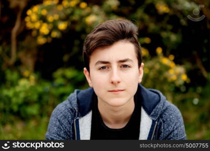 Attractive teenager guy in a park with green plants of background