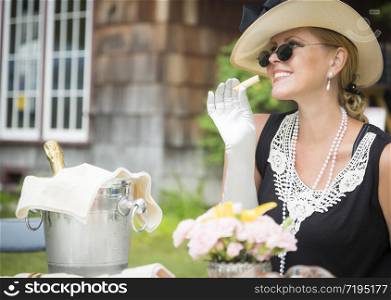 Attractive Twenties Dressed Woman Eating and Drinking Champagne At Outdoor Party.