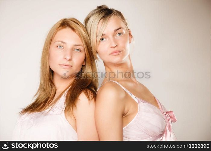 Attractive two blonde women with no makeup, fresh face with natural make up on gray