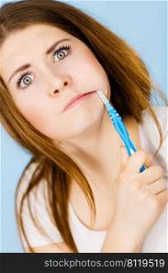 Attractive weird woman with long brown hair brushing her teeth with toothbrush. Studio shot blue background.. Weird woman brushing her teeth with toothbrush