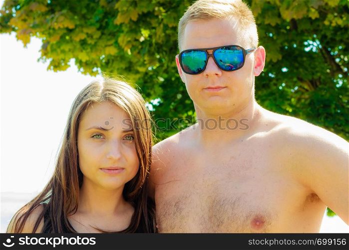 Attractive woman and man with sunglasses posing in summer clothes on sunny day. Man and woman posing in summer