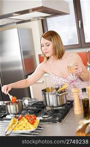 Attractive woman cooking spaghetti and tomato sauce in modern kitchen