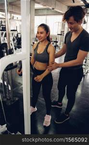 Attractive woman doing exercise with personal trainer at gym.
