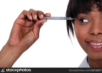 Attractive woman holding a pen to her head