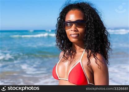 Attractive Woman in bikini standing in the sun on beach with sun glasses