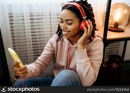 Attractive woman in headphones enjoys listen to music. Pretty lady in earphones relax in the room, female sound lover resting. Attractive woman in headphones enjoys music