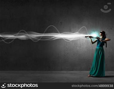 Attractive woman in long green dress playing violin. Elegant violinist player
