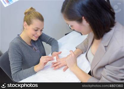 attractive woman in manicure salon polishing her nails by beautician