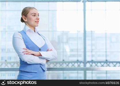 Attractive woman in office building. Young blond woman in modern glass interior arms crossed on chest