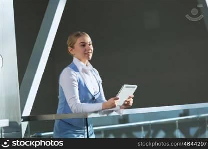 Attractive woman in office building. Young blond woman in modern glass interior using tablet
